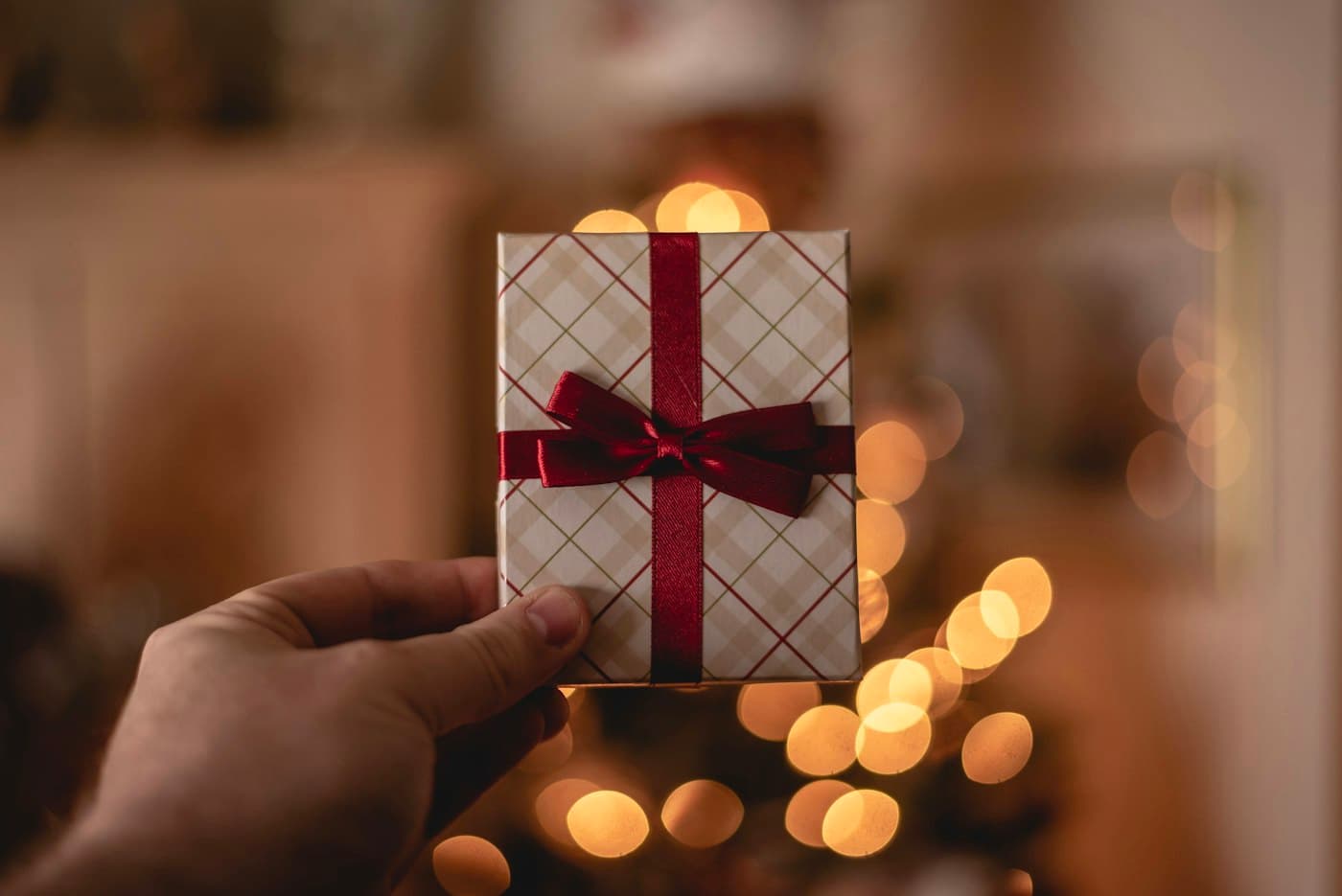 A hand holding up a gift card wrapped with a red ribbon