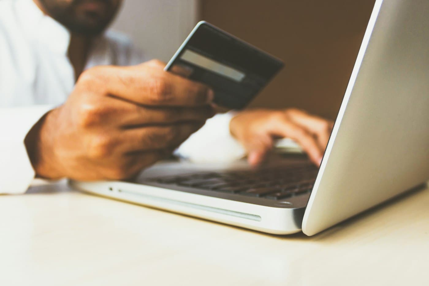 Someone shopping online on a laptop with a card in hand